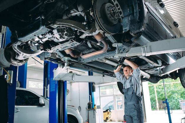 Retrato de um mecânico reparando um carro levantado