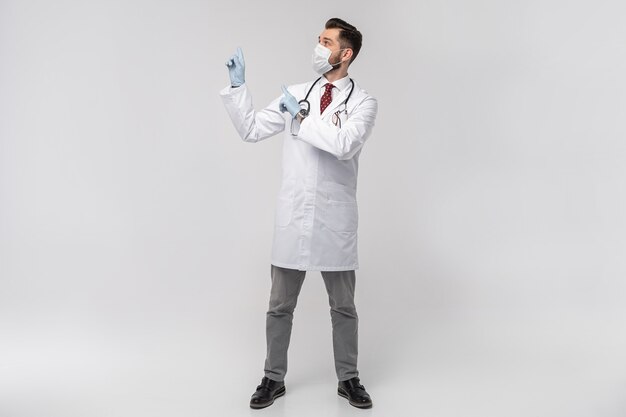 Retrato de um médico bonito atraente em máscara protetora, jaleco branco, gravata isolada na parede branca