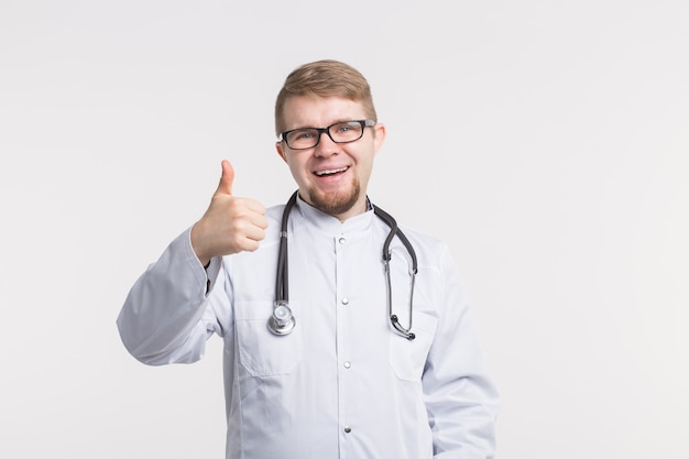 Retrato de um médico bonito mostrando os polegares sobre um fundo branco