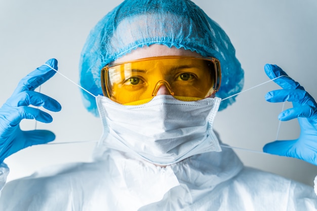 Retrato de um médico colocando uma máscara e uniforme azul. isolado no fundo branco pandemia 2019-ncov, novo coronavírus chinês, conceito wuhan coronavirus.