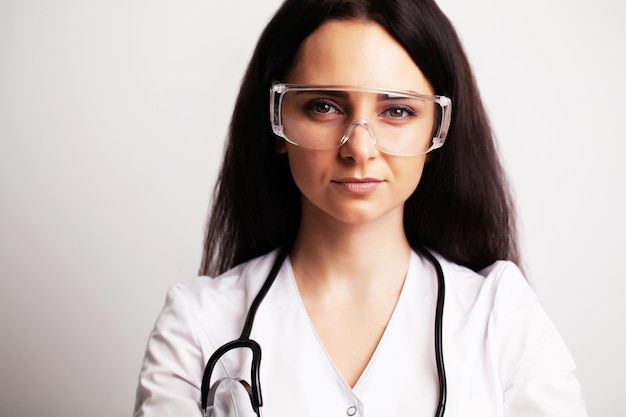 Retrato de um médico com óculos e uma bata branca, olhando para a câmera.