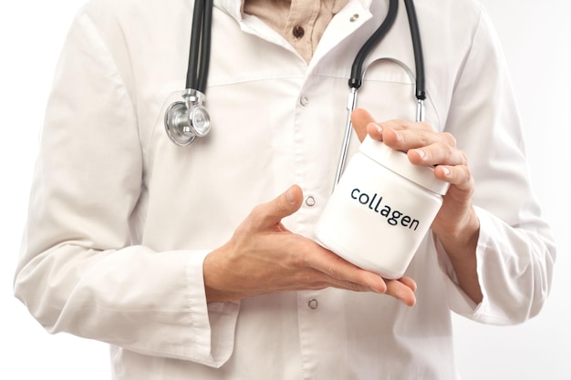 Retrato de um médico de jaleco branco demonstrando um frasco de colágeno isolado no fundo branco com espaço de cópia