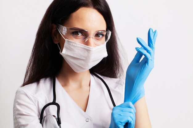 Retrato de um médico de óculos e uma bata branca de médico usando equipamento de proteção individual.