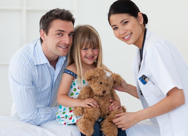 Retrato de um médico e uma menina feliz examinando um ursinho de pelúcia