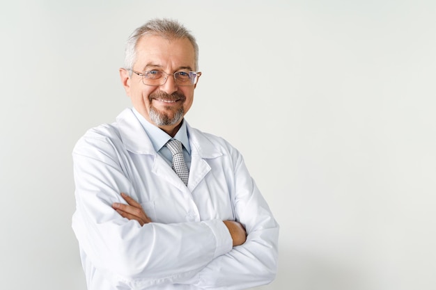 Retrato de um médico idoso em um médico amigável de fundo branco, sorrindo enquanto olha para