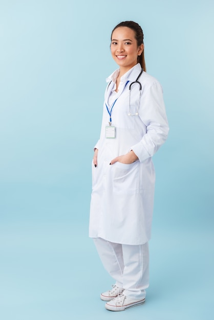 retrato de um médico jovem alegre feliz posando isolado sobre uma parede azul com estetoscópio.