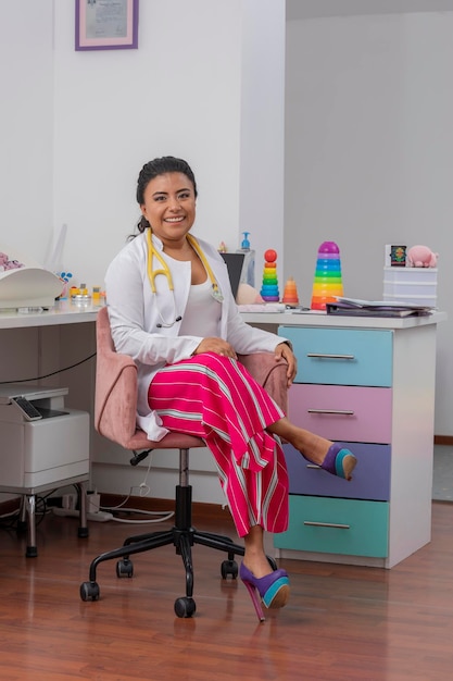 Retrato de um médico pediatra sorridente, sentado à mesa em seu escritório