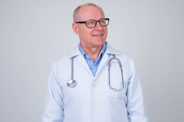 Retrato de um médico sênior bonito contra uma parede branca