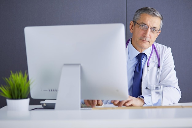 Foto retrato de um médico sênior sentado em um consultório médico