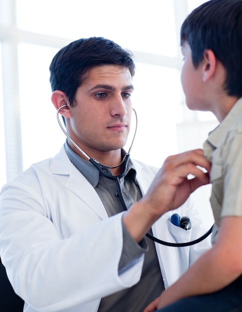 Retrato de um médico sério examinando um garotinho