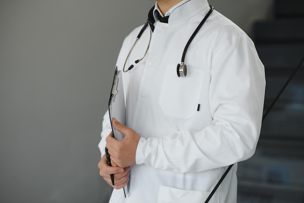 Retrato de um médico sorridente de uniforme em pé no salão da clínica de medicina