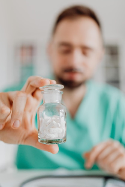 Retrato de um médico sorridente segurando uma garrafa com comprimidos ou pílulas para tratamento isolado em whi