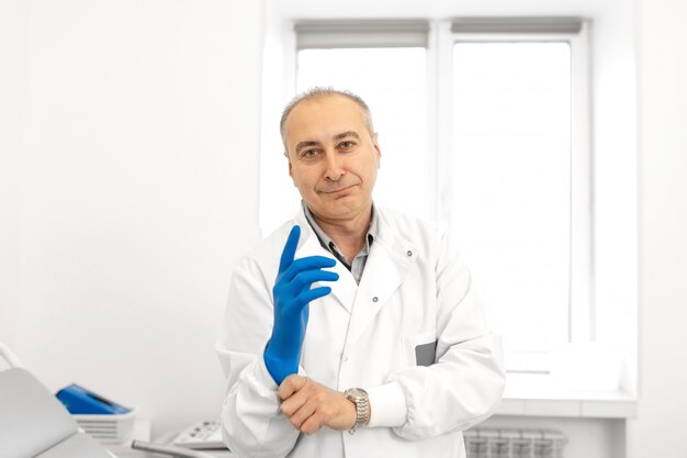 Retrato de um médico urologista calçar luvas médicas antes de examinar um paciente