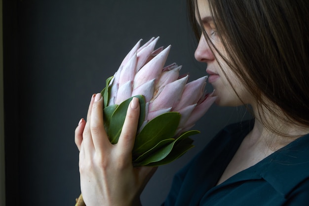 Retrato, de, um, menina, com, cabelo escuro, segura, um, rosa grande, protea