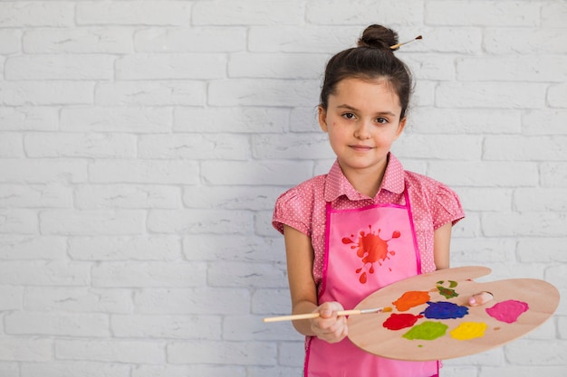 Foto retrato, de, um, menininha, segurando, multicoloured, paleta, e, escova, ficar, contra, parede branca