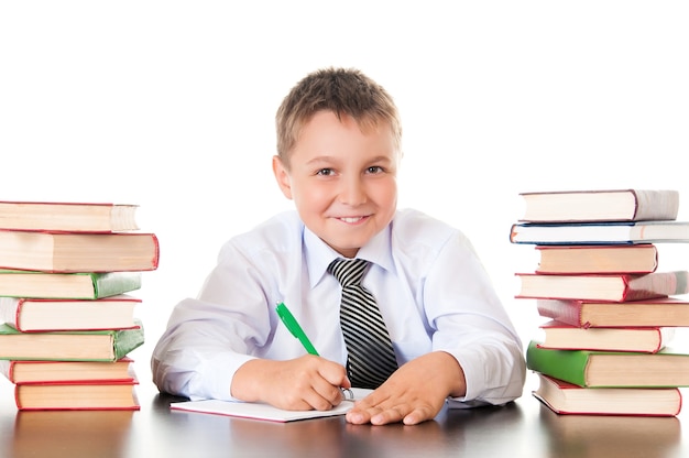 Retrato de um menino adolescente na escola na biblioteca perto de uma pilha de livros