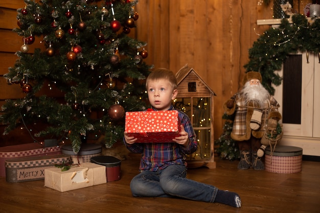 Retrato de um menino alegre perto da árvore de natal