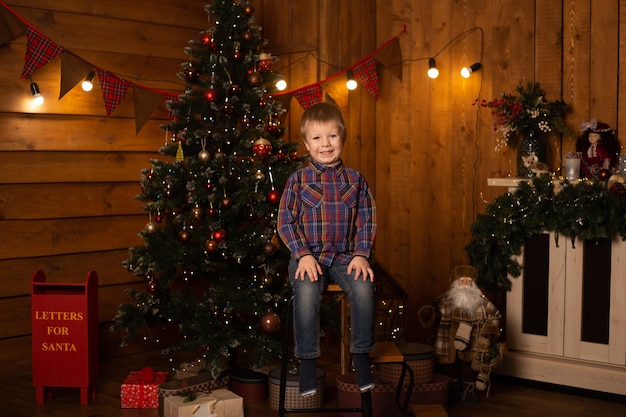 Retrato de um menino alegre perto da árvore de Natal