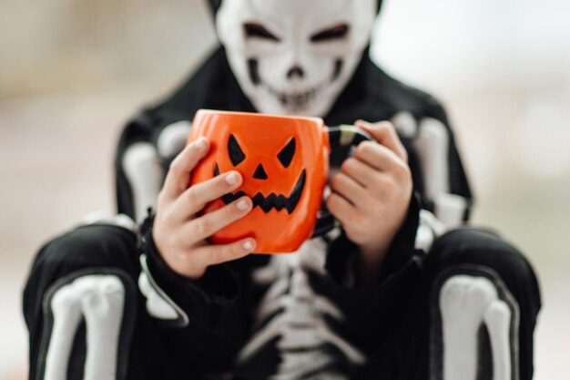 Retrato de um menino autêntico e sincero da geração Z se diverte com fantasia de esqueleto no feriado de Halloween