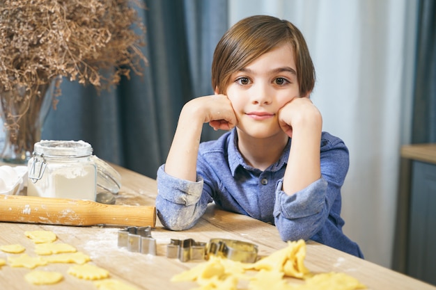 Retrato de um menino bonitinho cozinhar biscoitos caseiros na cozinha