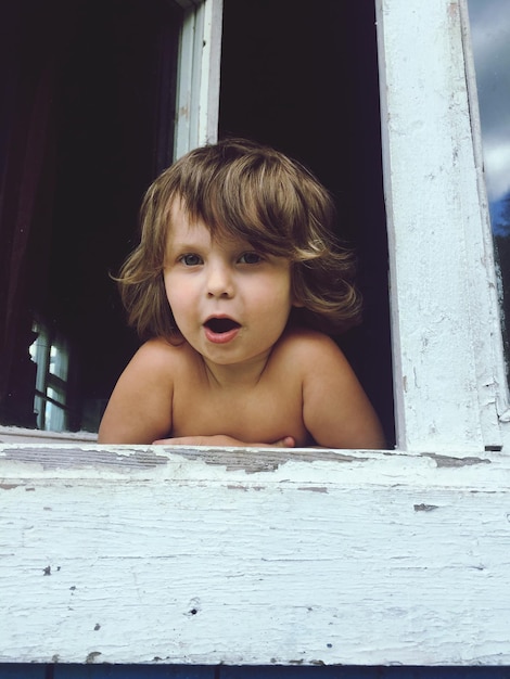 Foto retrato de um menino bonito apoiado na janela