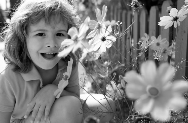 Retrato de um menino bonito com flores de primavera de perto crianças caucasianas rosto de perto cabeça de engraçado