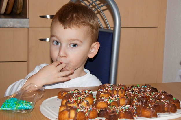 Foto retrato de um menino bonito comendo biscoitos na mesa em casa