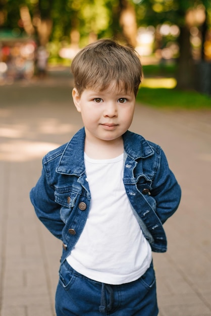 Retrato de um menino bonito de três anos em jeans no verão no parque