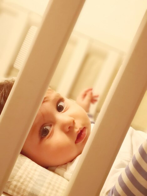 Foto retrato de um menino bonito deitado no berço em casa