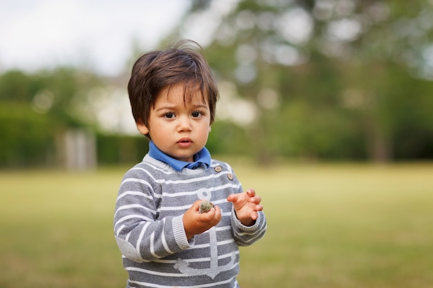 Retrato de um menino bonito oriental brincando ao ar livre no parque. Diversão de criança árabe na rua.