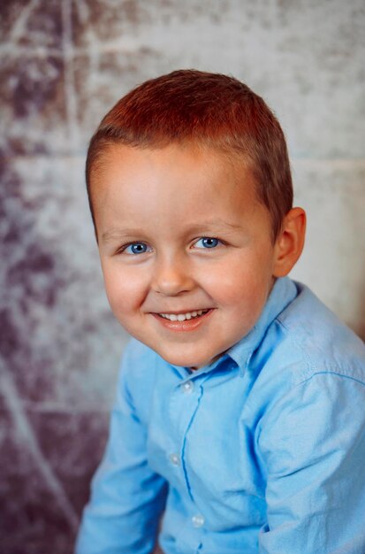 Foto retrato de um menino bonito sorridente em uma pessoa de camisa azul
