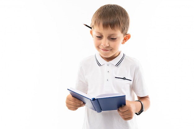 Retrato de um menino caucasiano em dúvida escrevendo algo no caderno e pensar