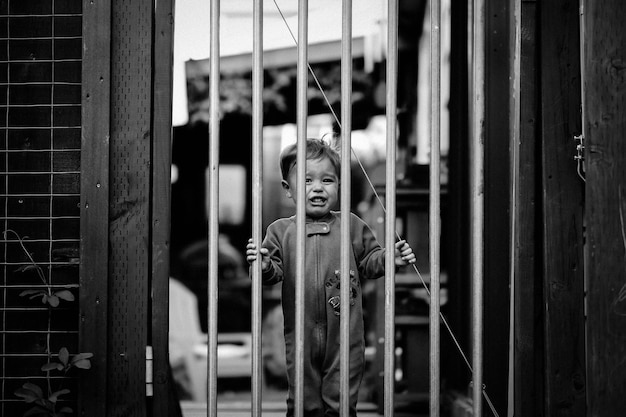 Foto retrato de um menino chorando de pé no portão