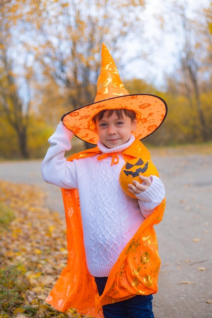 Retrato de um menino com roupas de Halloween com uma abóbora na rua Um feriado tradicional 31 de outubro