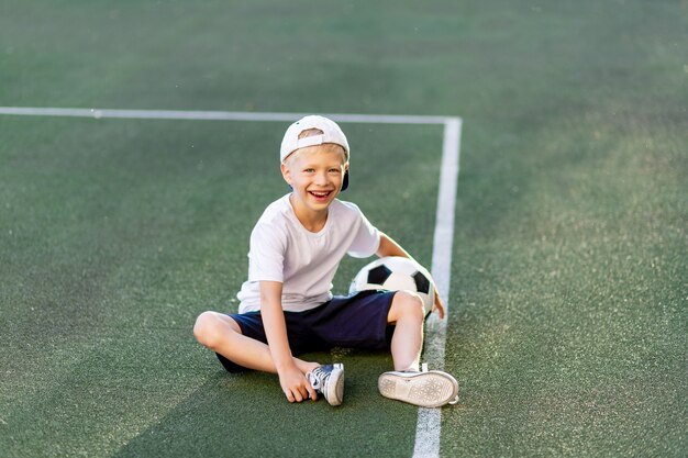 Retrato de um menino com uma bola de futebol nas mãos no campo de futebol