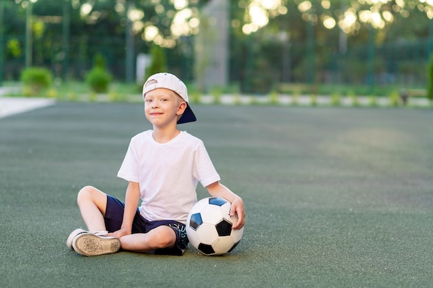 Retrato de um menino com uma bola de futebol nas mãos no campo de futebol