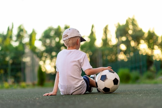 Foto retrato de um menino com uma bola de futebol nas mãos no campo de futebol