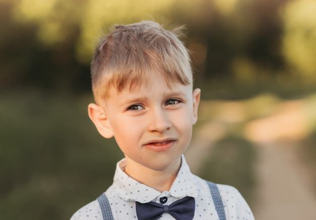 Retrato de um menino com uma camisa na natureza no verão