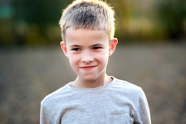 Retrato de um menino criança ao ar livre em um dia quente de verão ensolarado.