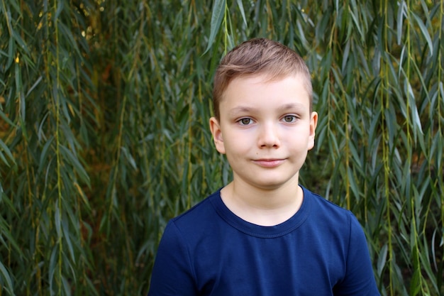 Foto retrato de um menino de 9 anos contra o fundo de folhas de salgueiro bonito menino caucasiano