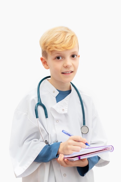 Retrato de um menino disfarçado de médico segurando um livro e uma caneta contra um fundo branco