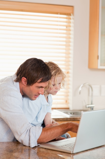 Retrato de um menino e seu pai usando um laptop juntos