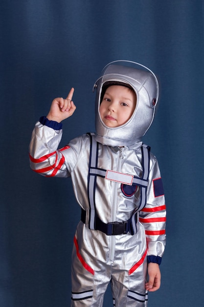 Foto retrato de um menino em traje de cosmonauta e capacete com o dedo indicador levantado