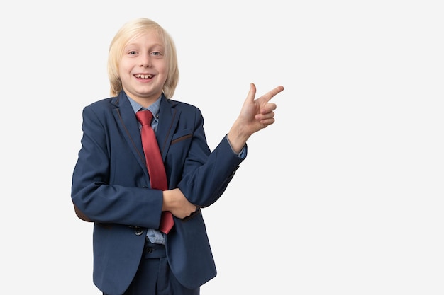 Retrato de um menino em um terno de negócios apontando para o espaço de cópia isolado em fundo branco
