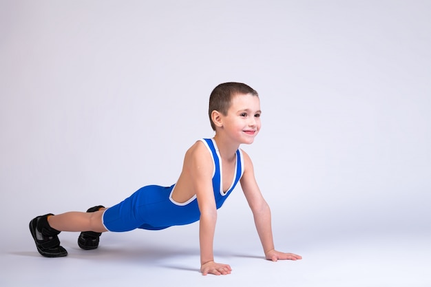 Retrato de um menino em uma meia-calça azul wrestling ep fica nas mãos em uma pose de flexão, olha para a frente e coloca em um branco isolado