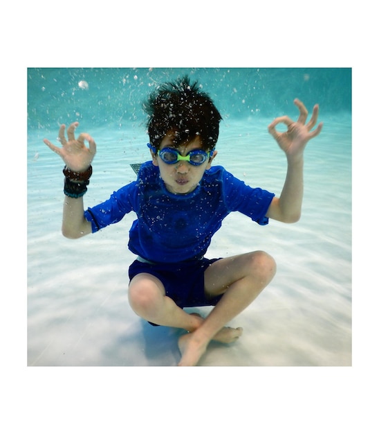Foto retrato de um menino fazendo gestos na piscina