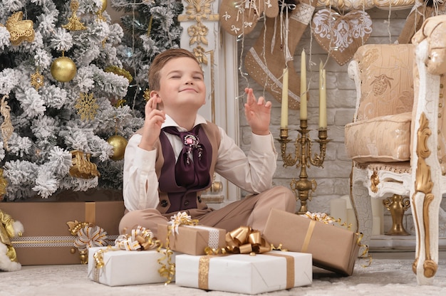 Retrato de um menino fazendo um desejo perto da árvore de Natal