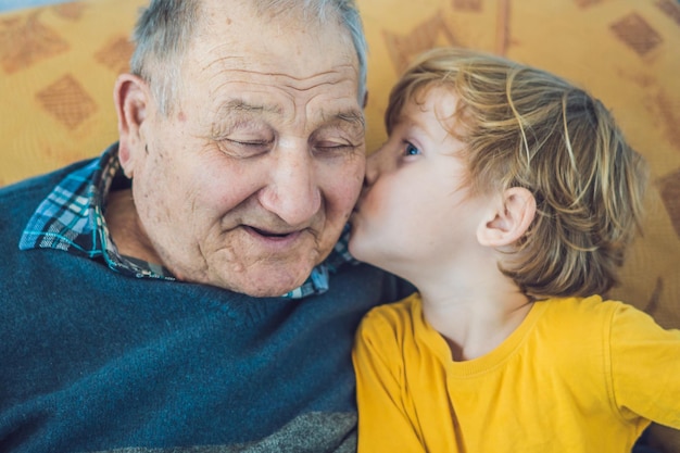 Retrato de um menino feliz beijando o avô feliz