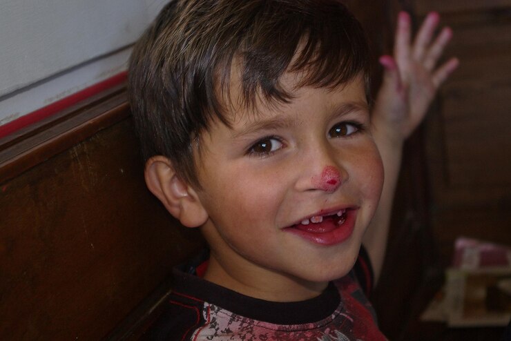 Foto retrato de um menino feliz com sangue no nariz