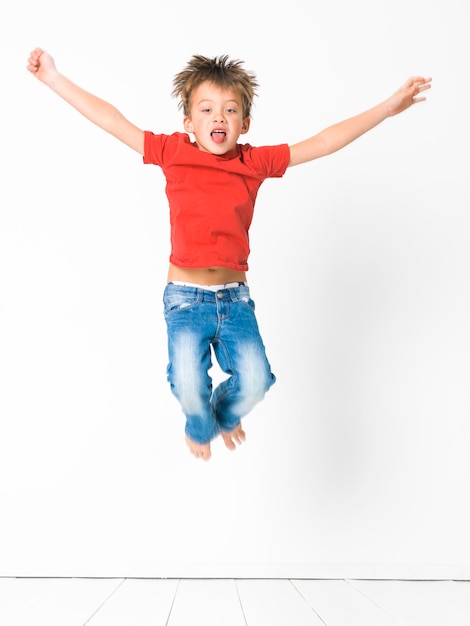 Foto retrato de um menino feliz pulando contra um fundo branco
